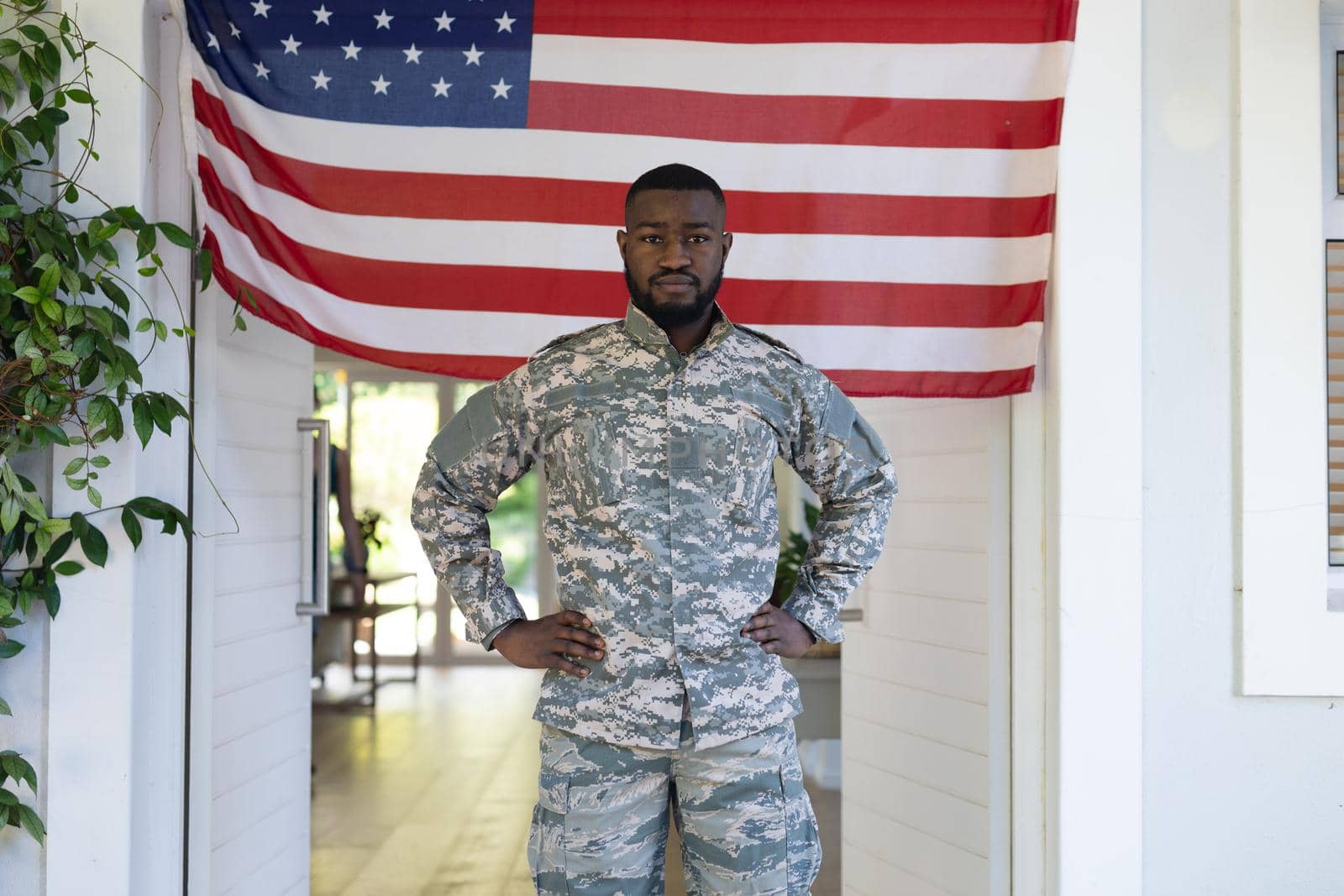 African american male soldier standing in front of american flag outside home. . soldier returning home to family.