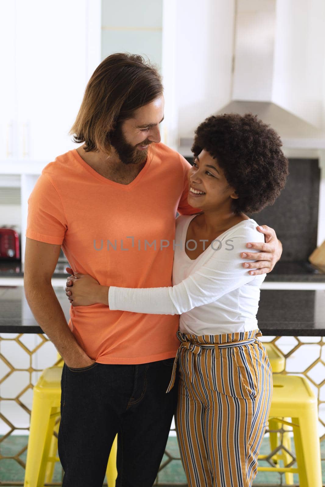 Happy diverse couple in kitchen smiling and embracing by Wavebreakmedia