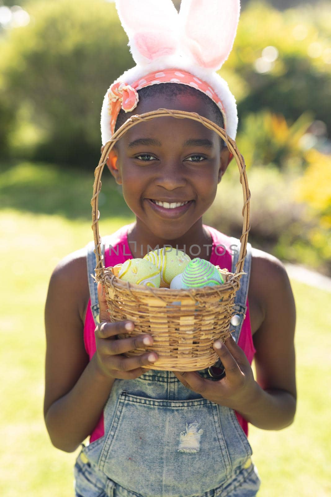 Portrait of african american girl holding basket while easter egg hunting. celebrating easter at home in isolation during quarantine lockdown.