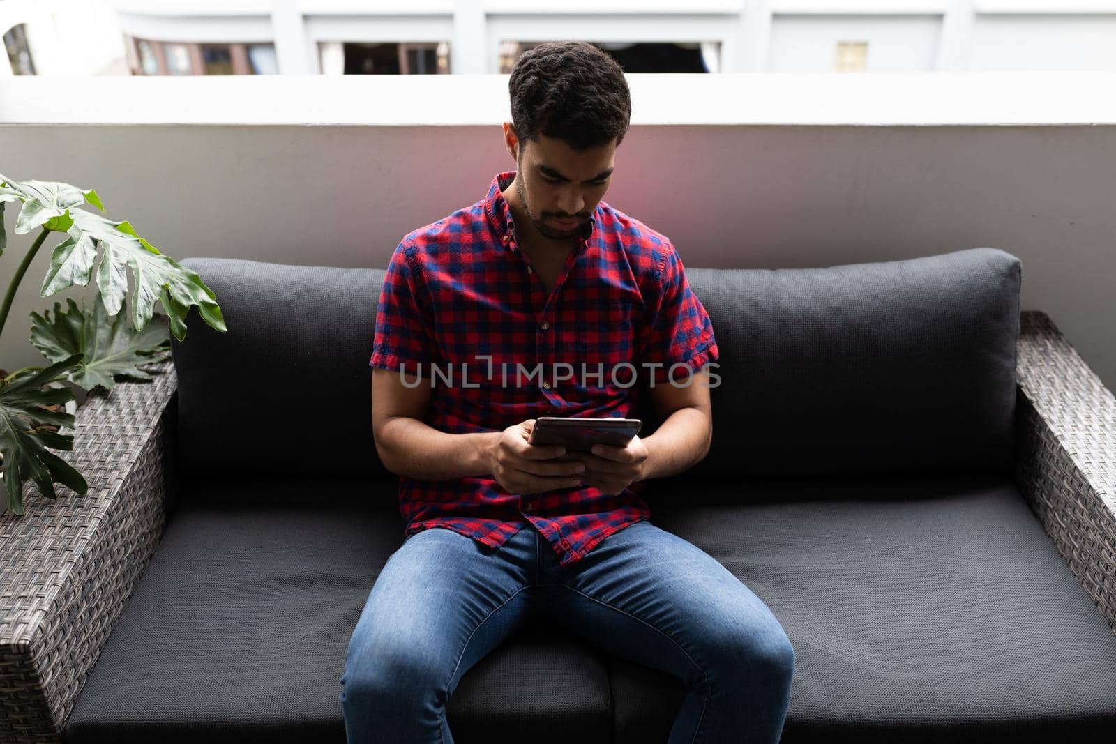 Mixed race businessman working in creative office. man sitting and using tablet. social distancing in workplace during covid 19 pandemic.