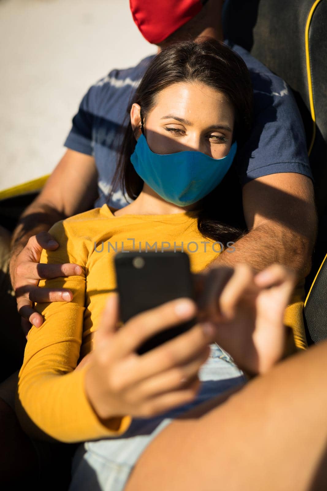 Happy caucasian couple wearing face masks sitting in beach buggy taking selfies by Wavebreakmedia