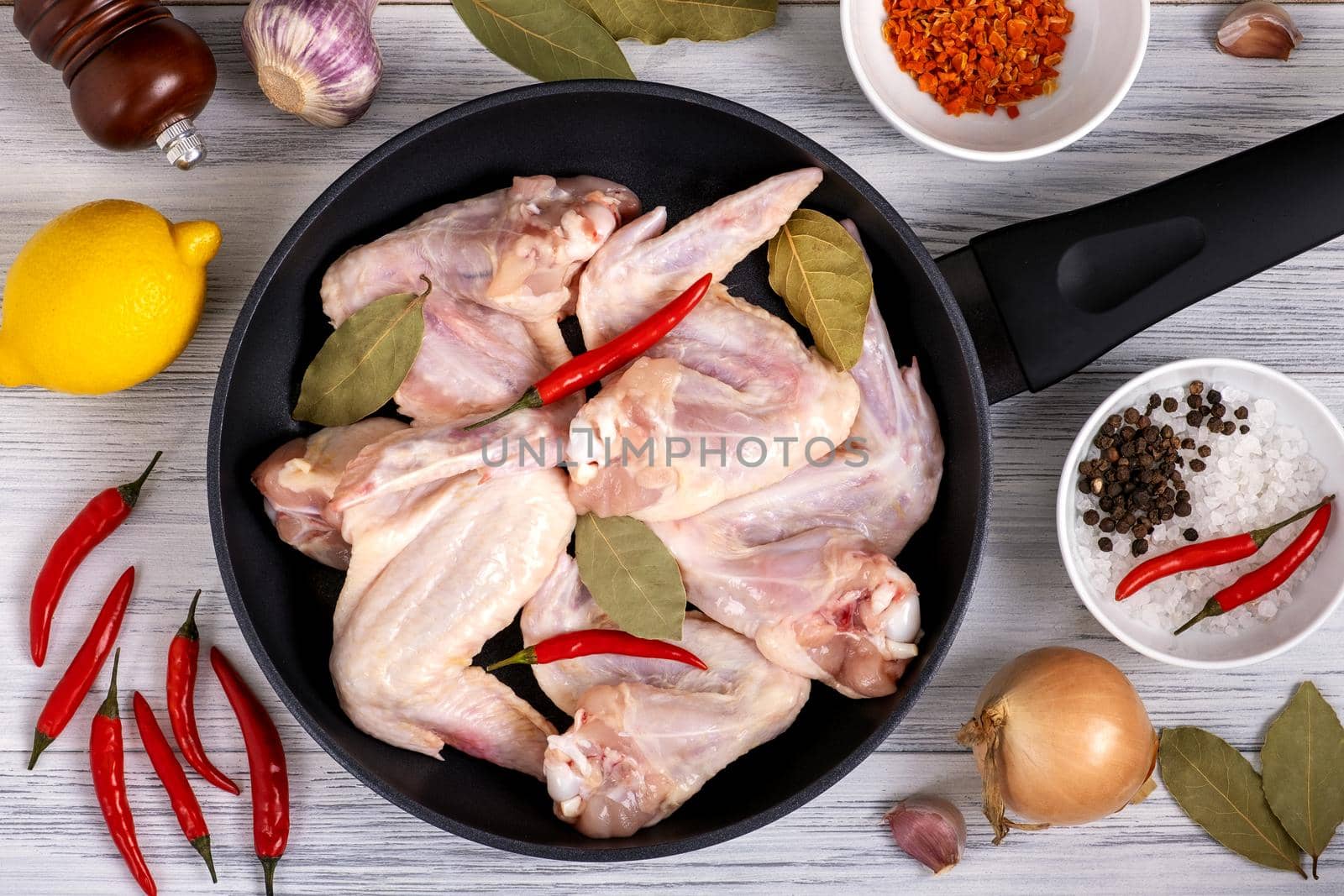 Close-up top view frying pan with raw chicken wings with spices. Ingredients for cooking chicken meat. Selective focus.