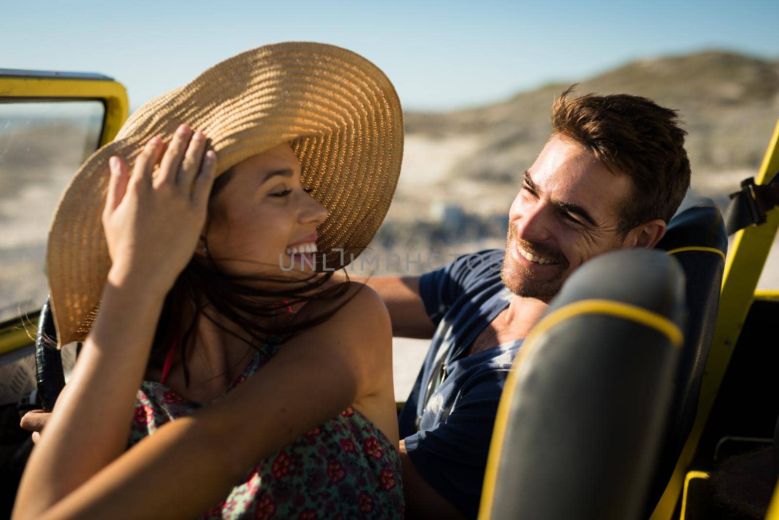 Happy caucasian couple sitting in beach buggy by the sea smiling. beach break on summer holiday road trip.