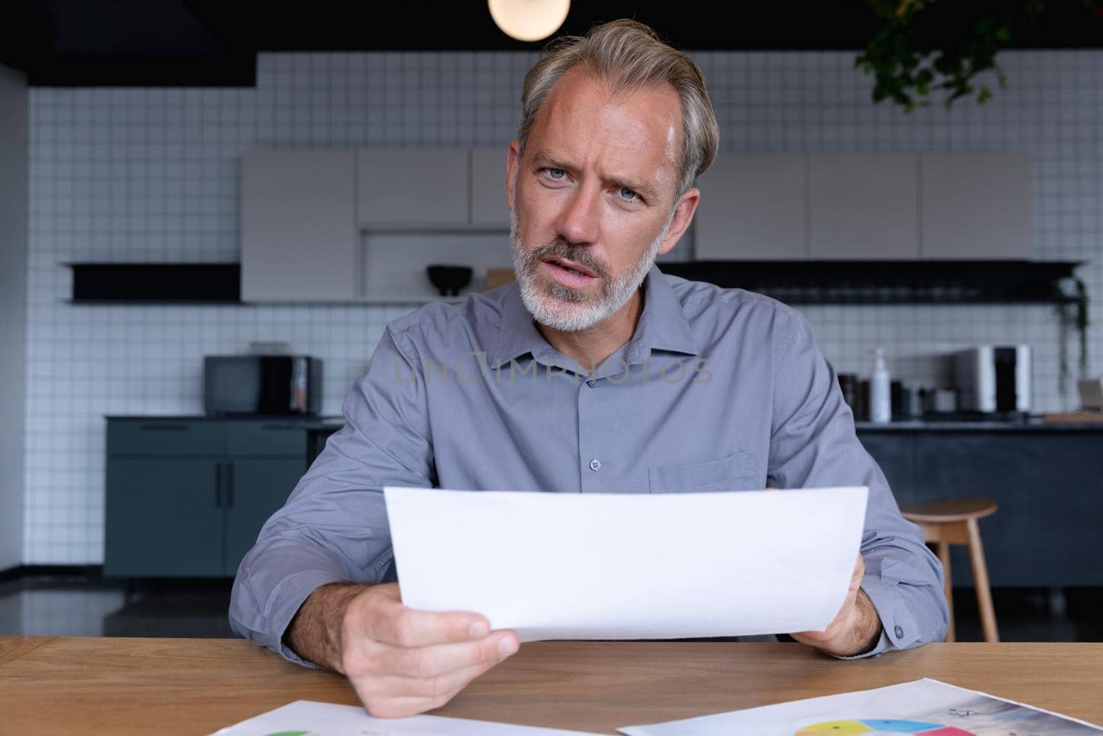 Caucasian businessman sitting having video chat going through paperwork in modern office by Wavebreakmedia