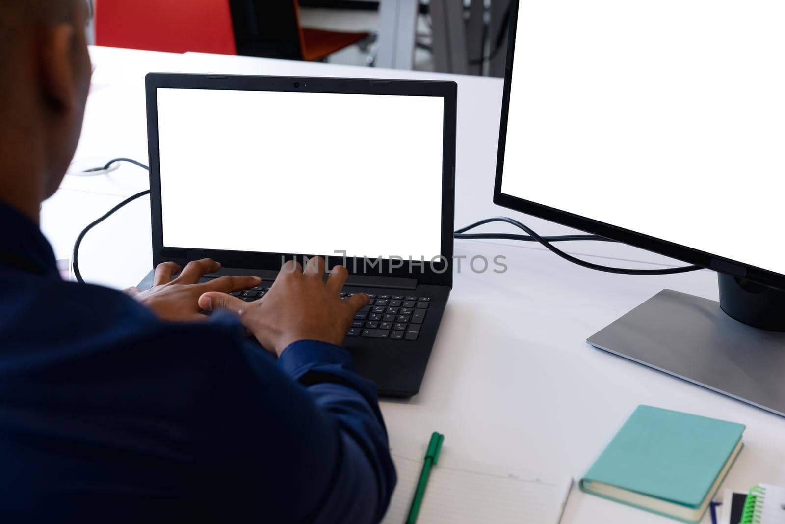 Mxed race businessman sitting using laptop and computer in a modern office by Wavebreakmedia