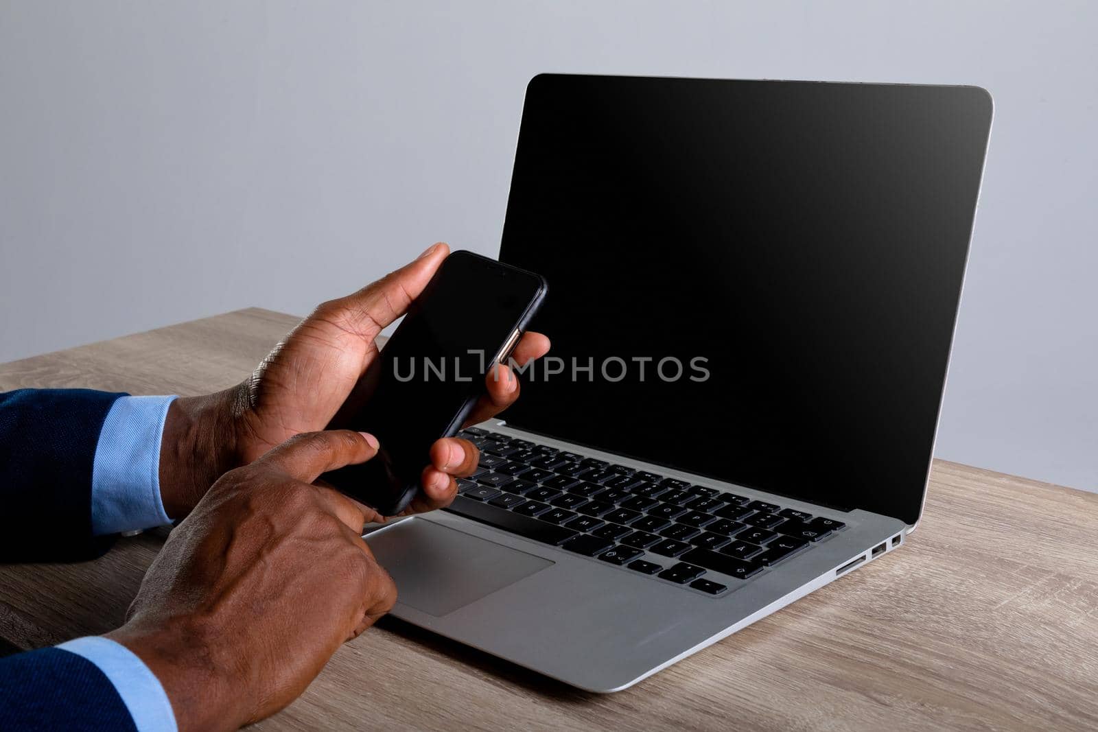 Close up of african american businessman using smartphone and laptop against grey background by Wavebreakmedia
