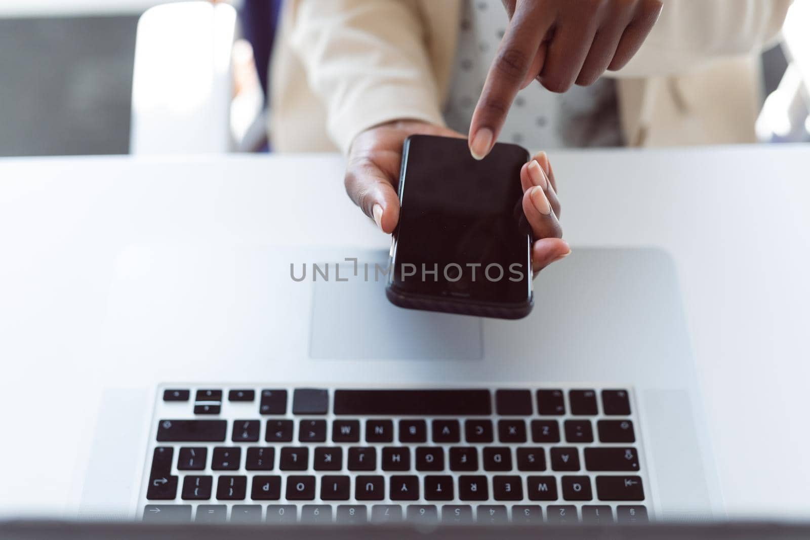 African american woman using smartphone with copy space on screen. independent creative business at a modern office.