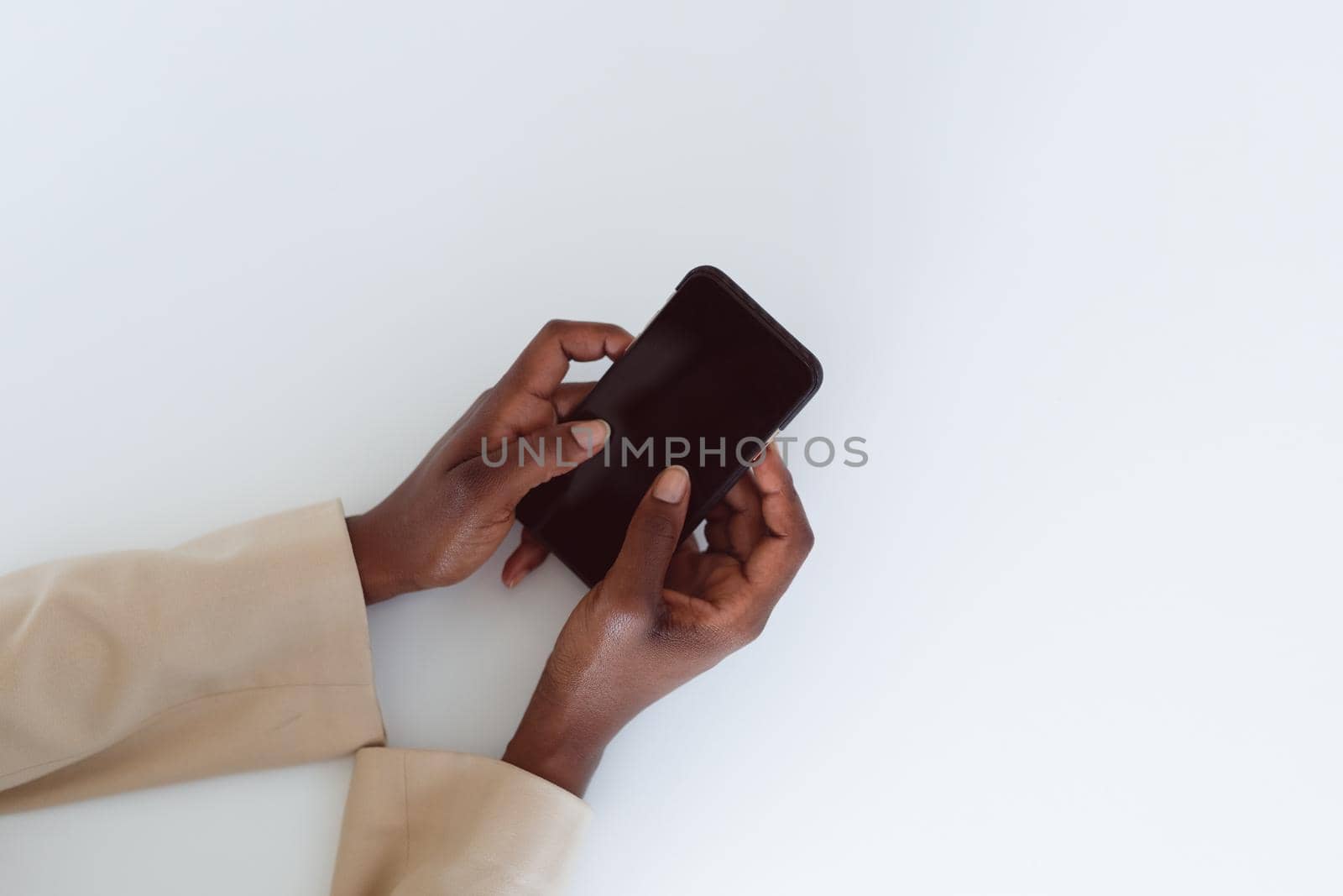 Hand of african american woman holding smartphone with copy space on screen. independent creative business at a modern office.