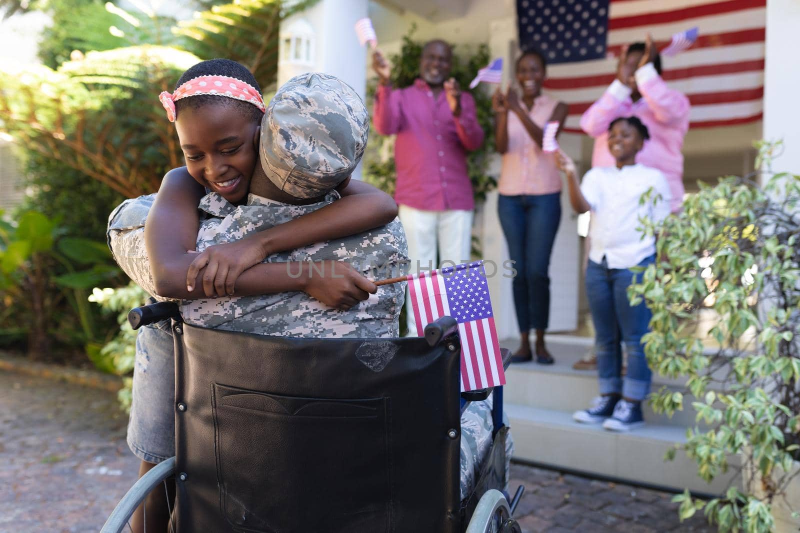 African american soldier father in wheelchair hugging daughter three generation family behind. soldier returning home to family.
