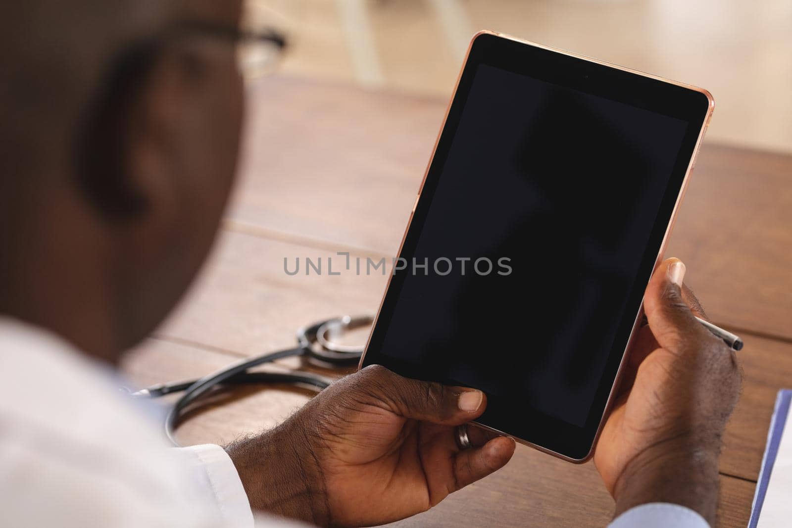 Mid section of african american senior male doctor holding digital tablet with copy space at home by Wavebreakmedia