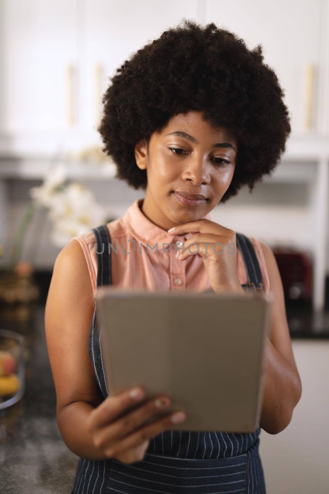 African american woman in kitchen using tablet by Wavebreakmedia