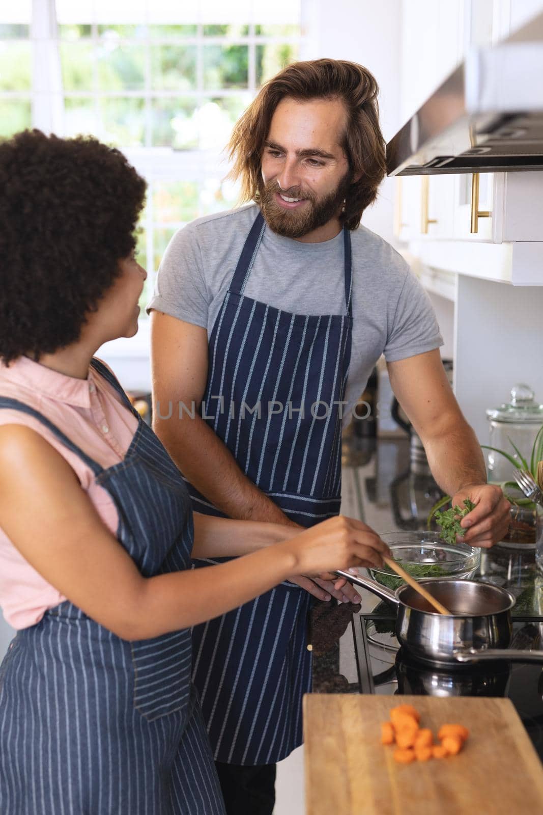 Happy diverse couple in kitchen preparing food and smiling by Wavebreakmedia