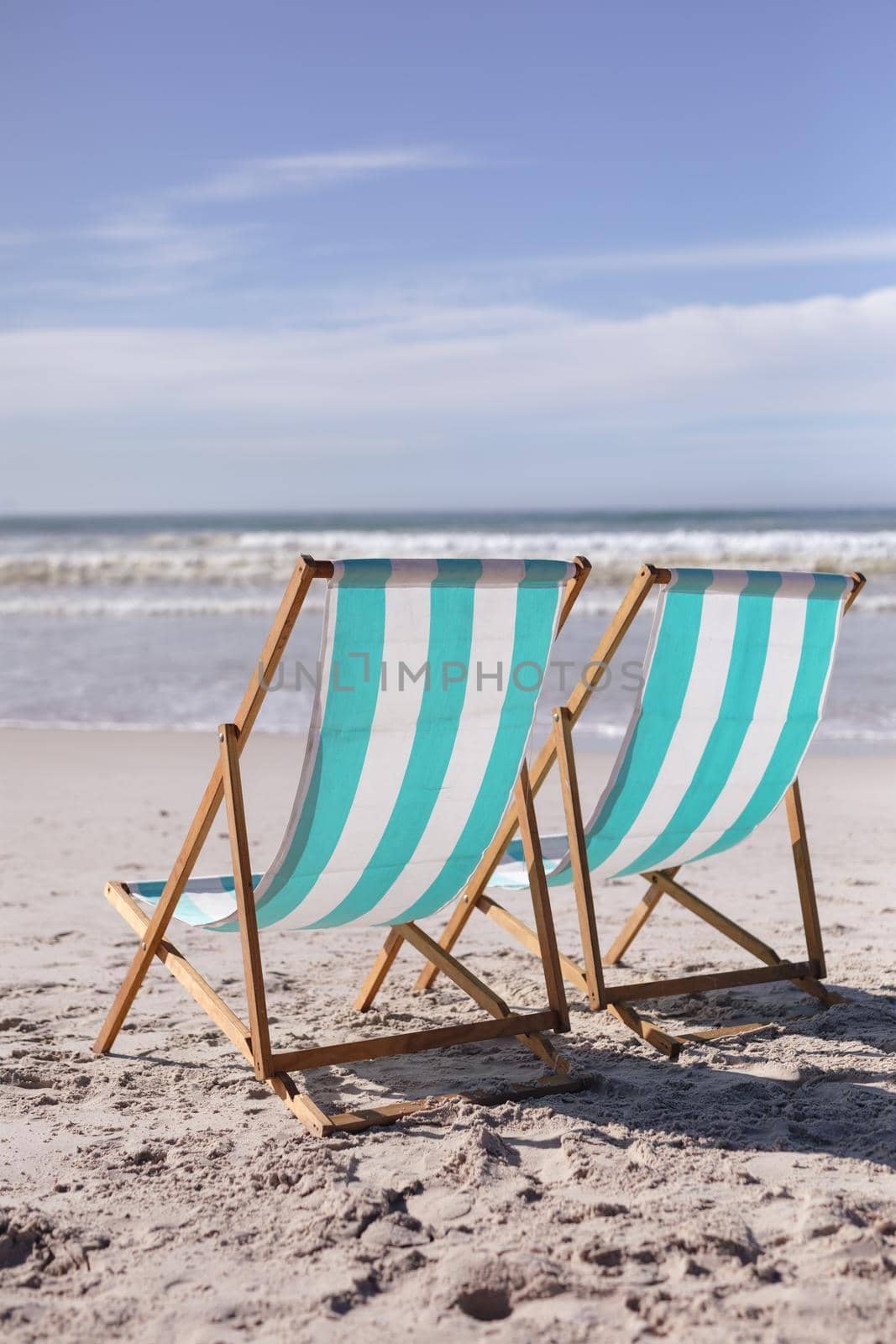 View of two deck chairs on the beach with sea waves by Wavebreakmedia