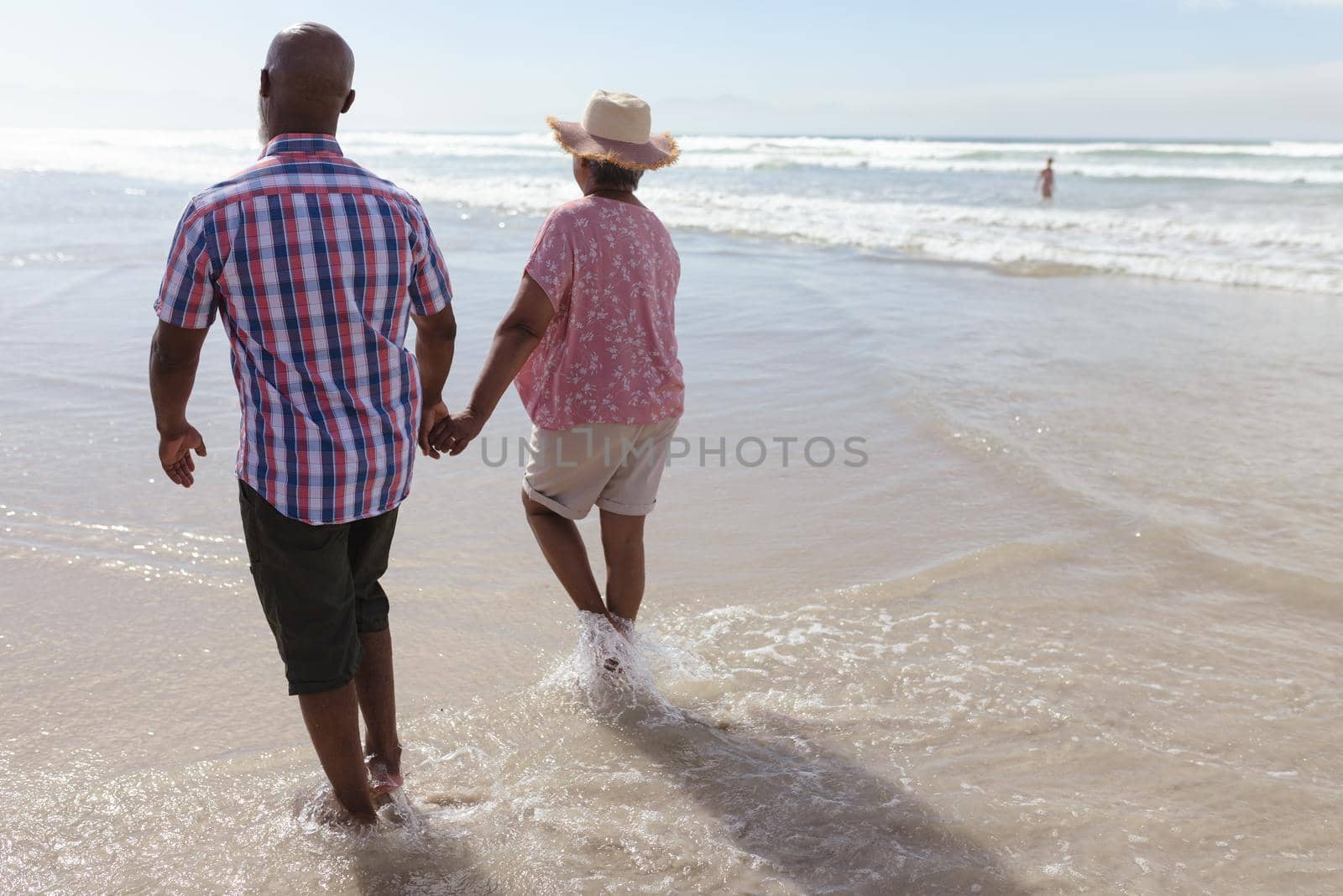Senior african american couple holding hands walking on the beach. travel vacation retirement lifestyle concept