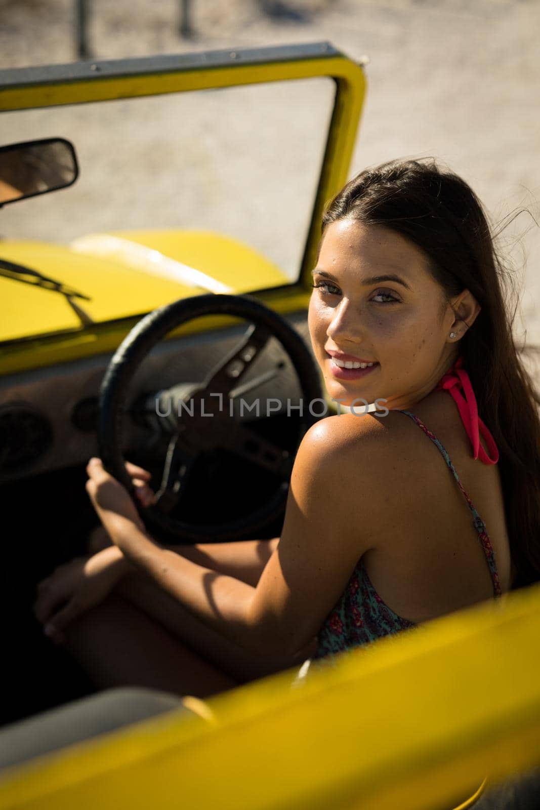 Happy caucasian woman sitting on beach buggy by the sea looking to camera by Wavebreakmedia