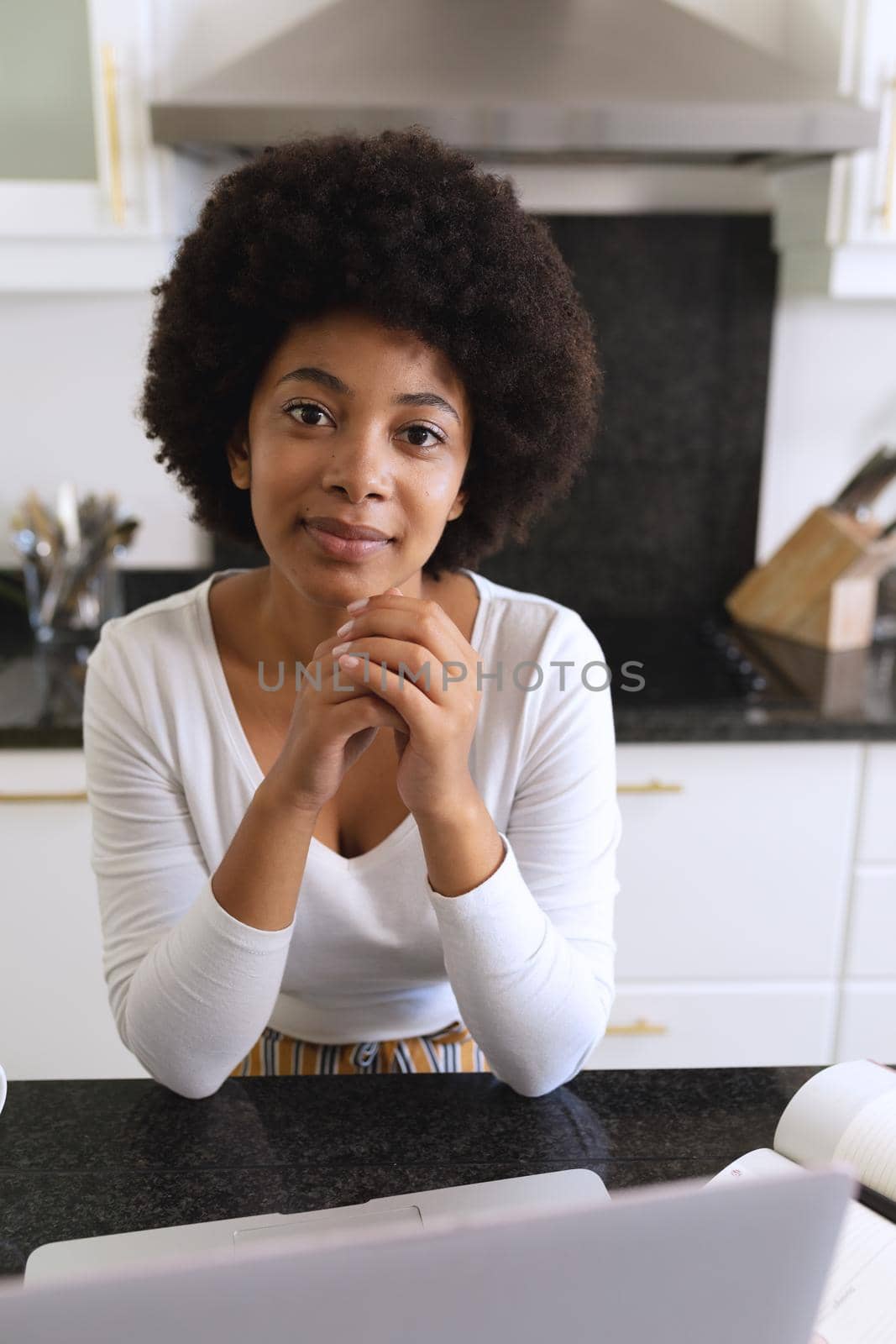 Portrait of african american woman sitting in kitchen smiling by Wavebreakmedia