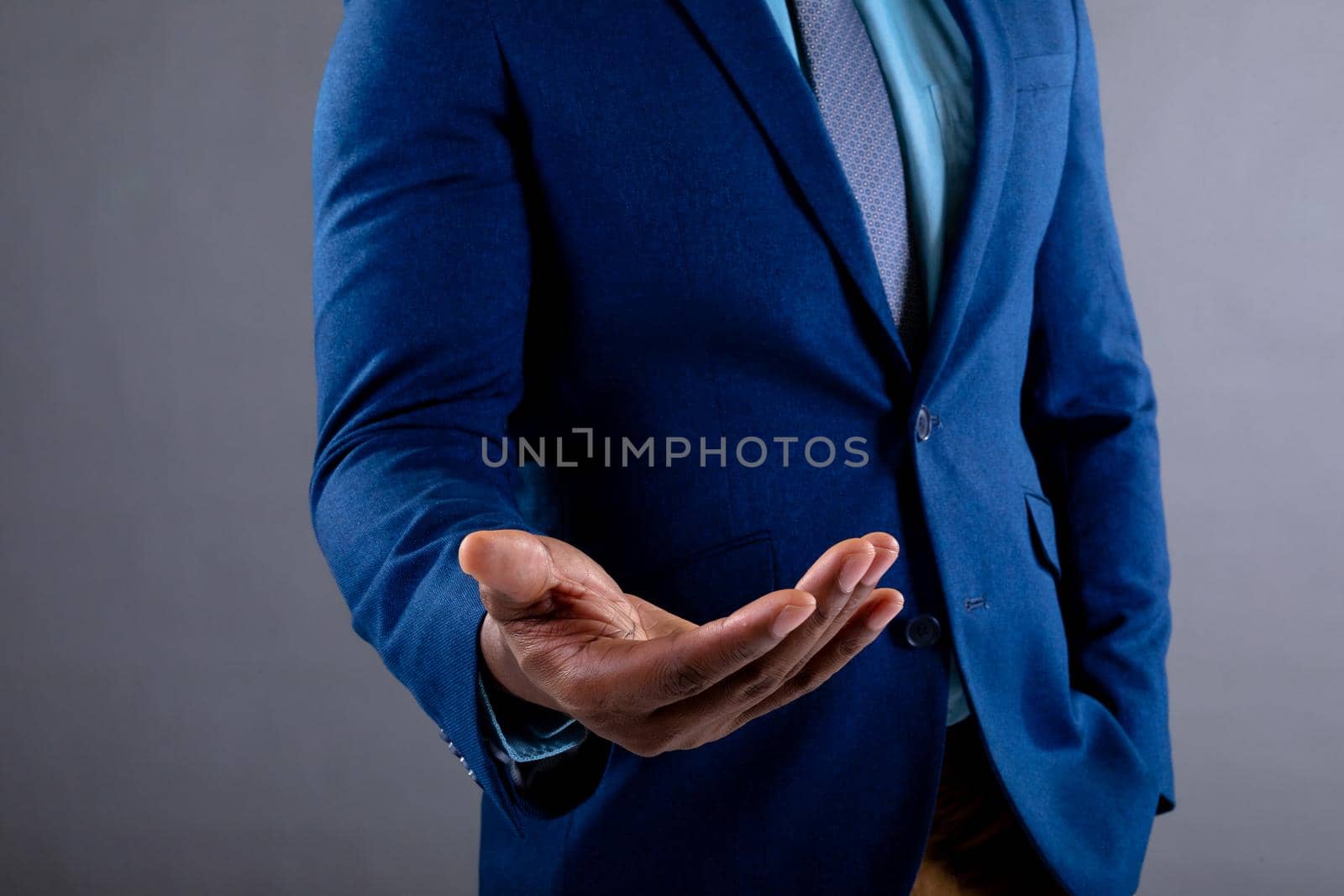 Mid section of african american businessman with cupped hand against grey background by Wavebreakmedia