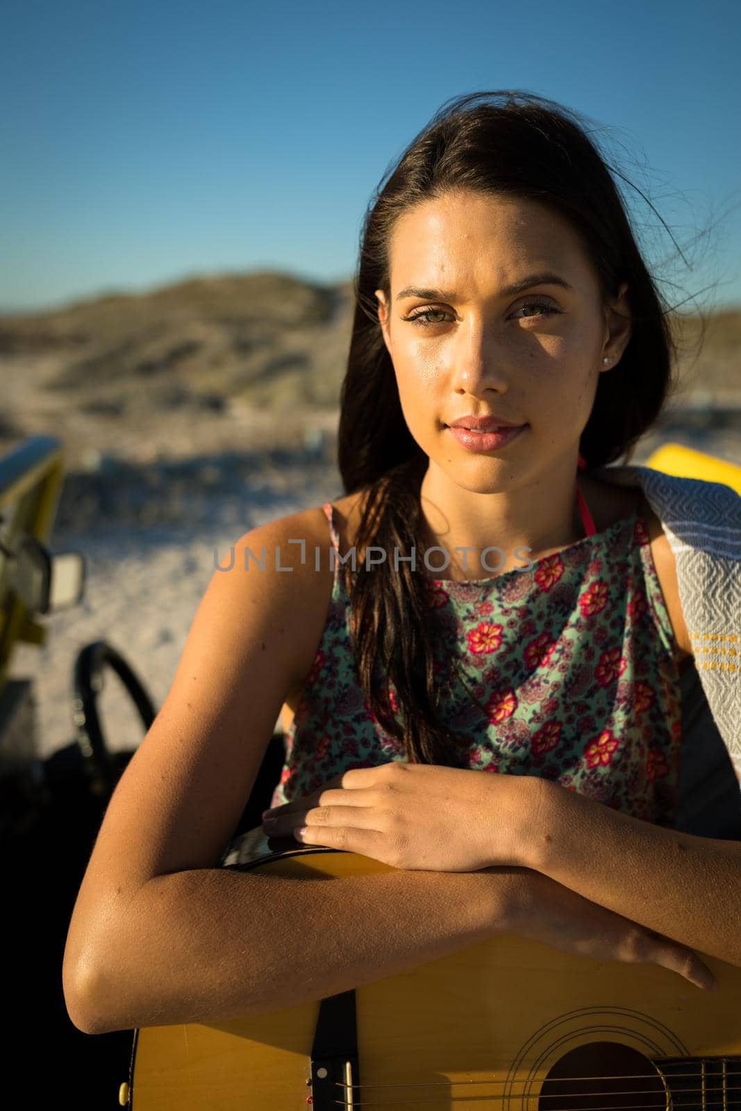 Portrait of happy caucasian woman on the beach holding guitar looking to camera by Wavebreakmedia