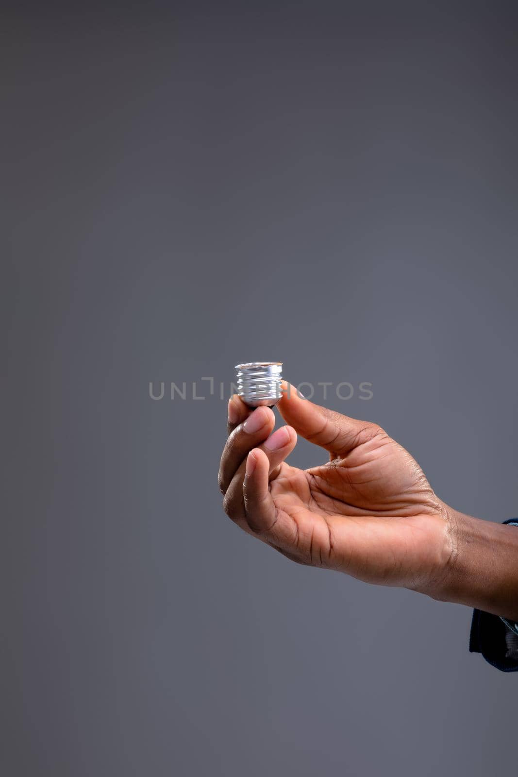 Close up of businessman holding bulb screw base against grey background. business, professionalism and technology concept