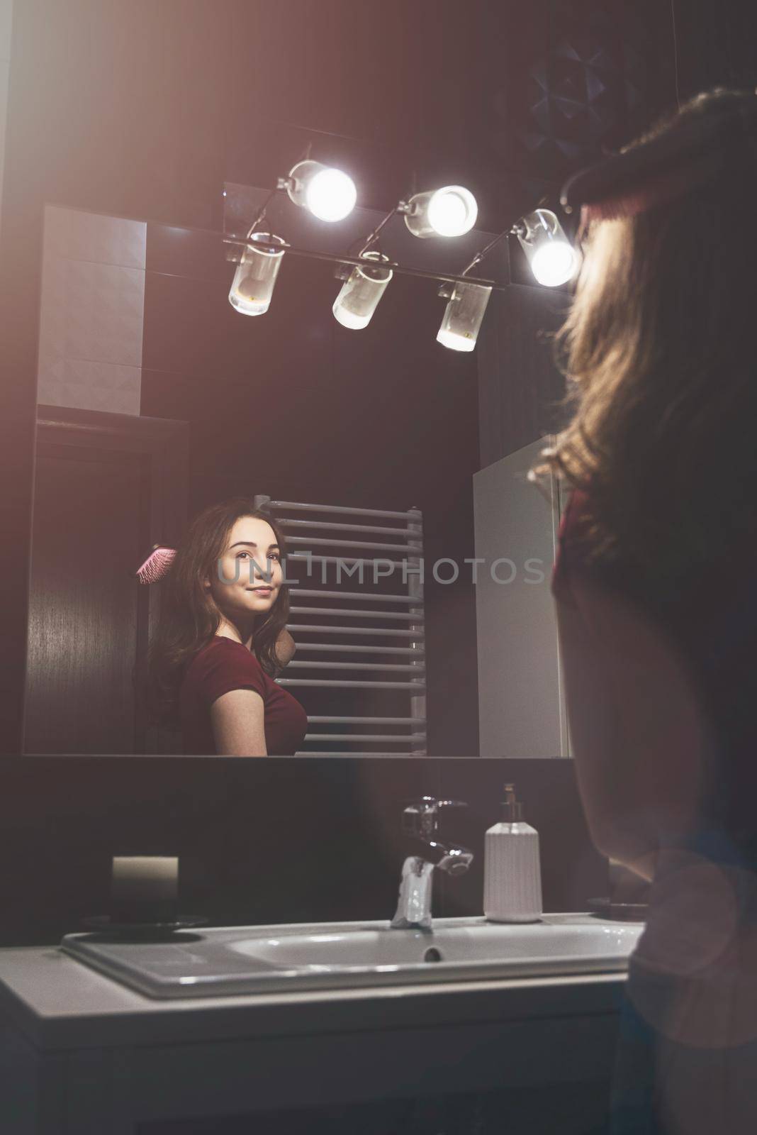 Young woman brushing hair in front of a bathroom mirror. by Ashtray25