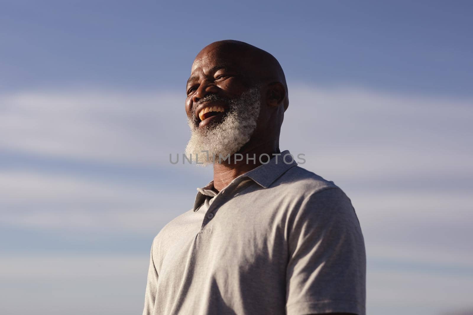 Senior african american man smiling while standing on the beach by Wavebreakmedia