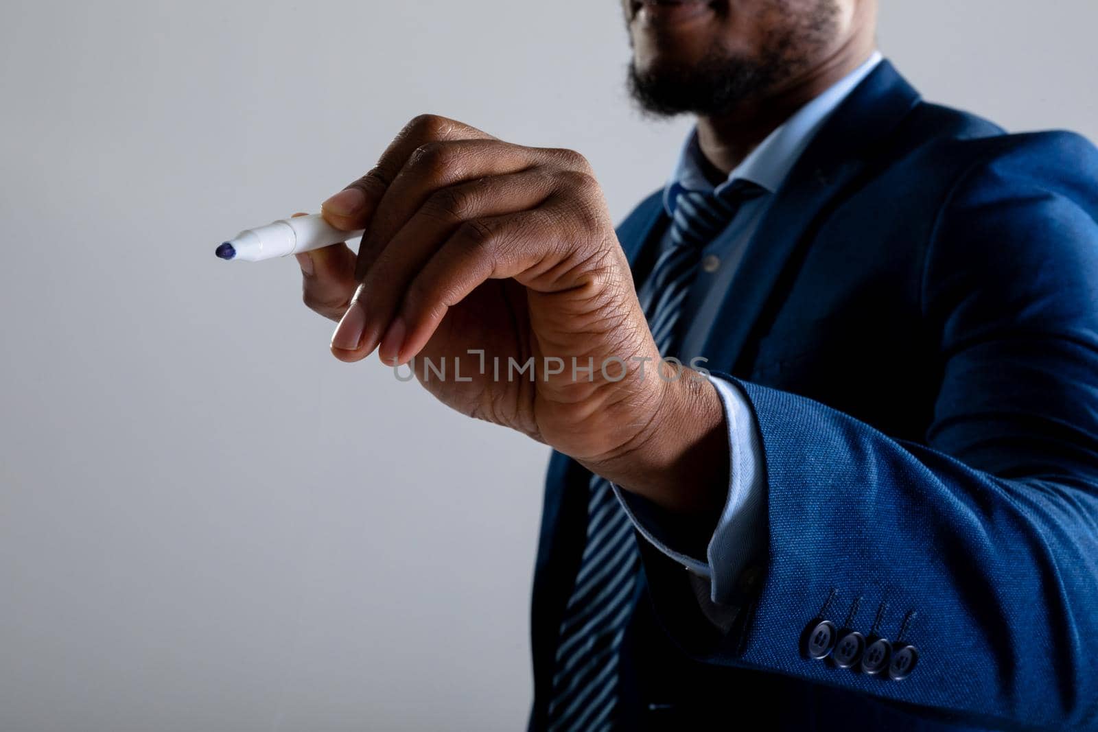 Mid section of businessman writing on invisible screen against grey background. business, professionalism and technology concept