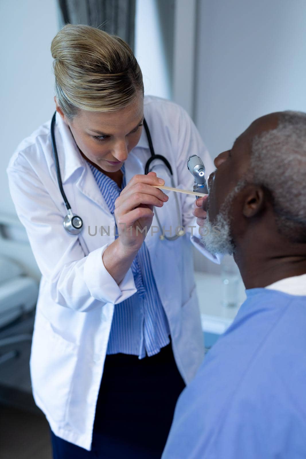 Caucasian female doctor examining throat of african american male patient by Wavebreakmedia