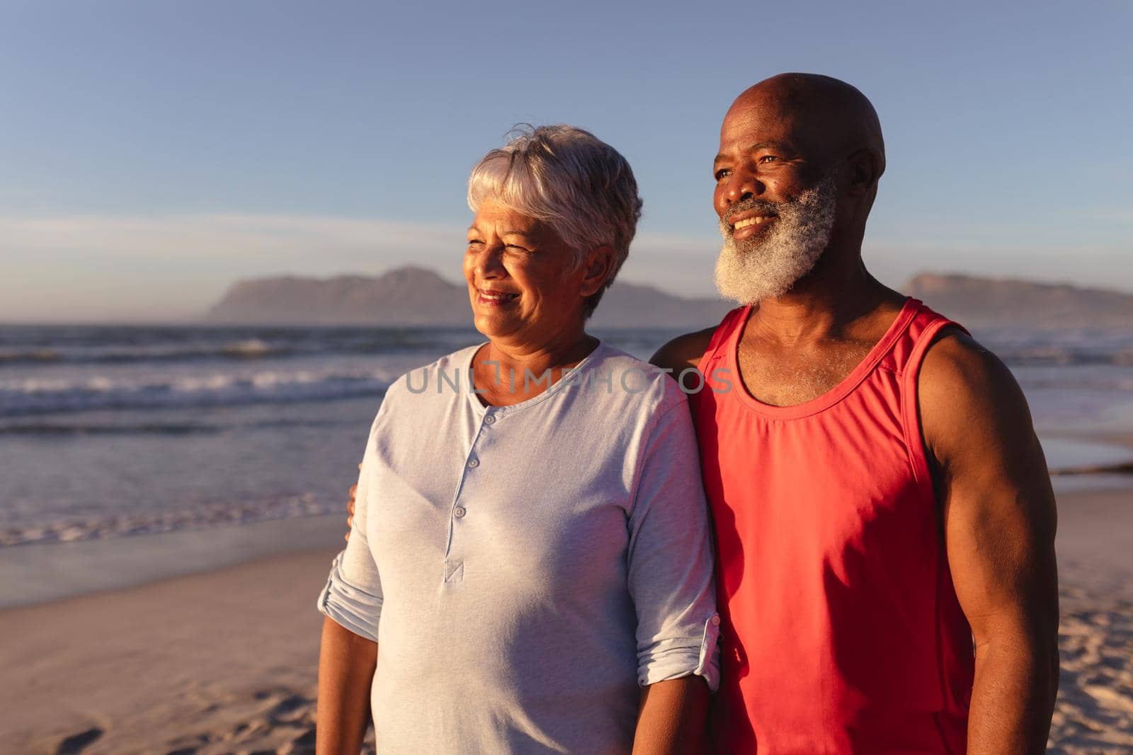 Senior african american couple smiling while standing on the beach. travel vacation retirement lifestyle concept