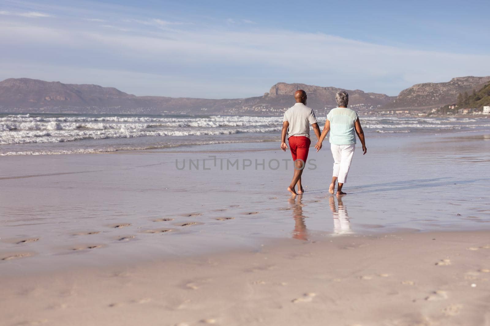 Senior african american couple holding hands while walking on the beach by Wavebreakmedia
