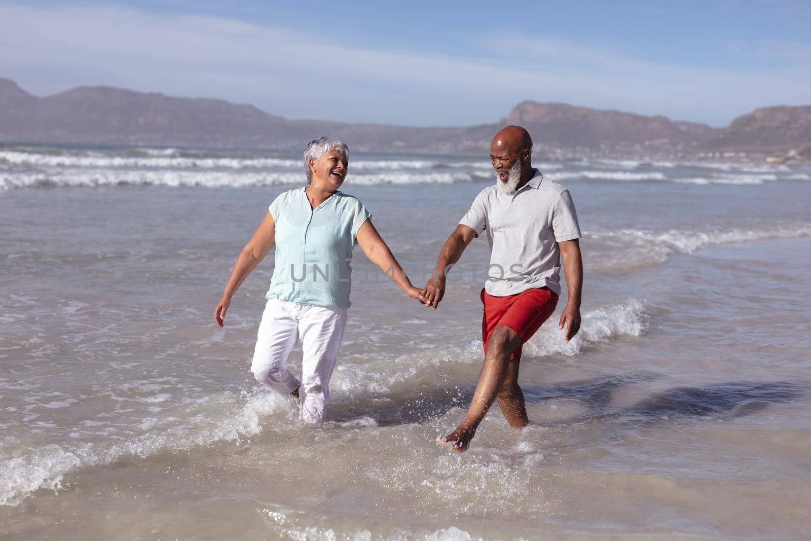 Happy senior african american couple holding hands and having fun on the beach by Wavebreakmedia