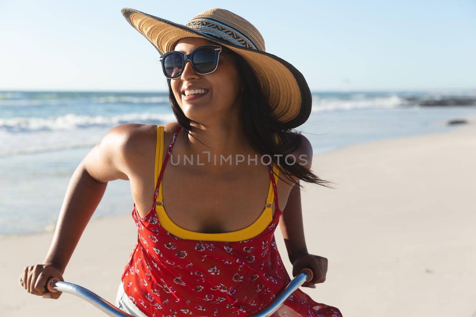 Happy mixed race woman having fun on beach holiday on bicycle. outdoor leisure vacation time by the sea.