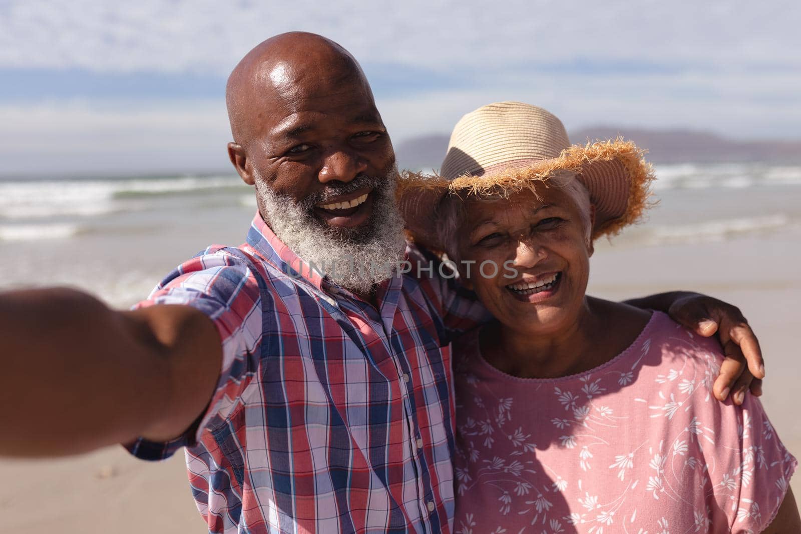 Portrait of happy senior african american couple taking a selfie at the beach. travel vacation retirement lifestyle concept