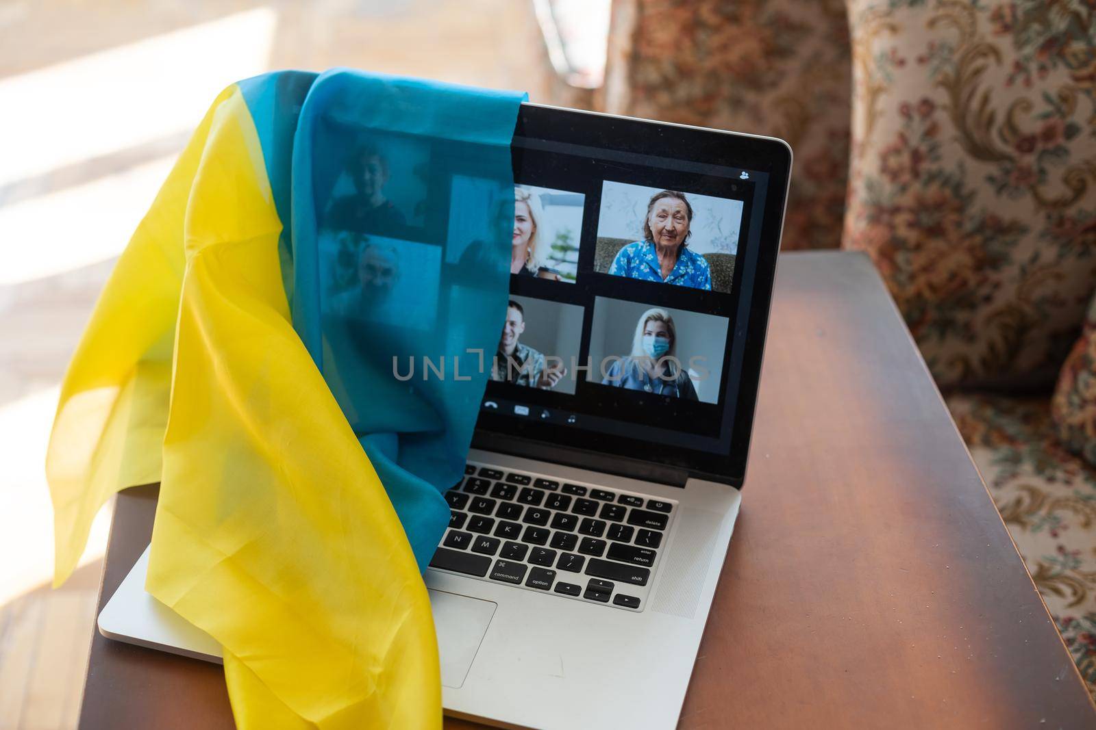 Flag of Ukraine on the background and wide digital screen of laptop with video conference. War with Russia. Cyber attack, sanctions, economic collapse. Message for world peace. by Andelov13
