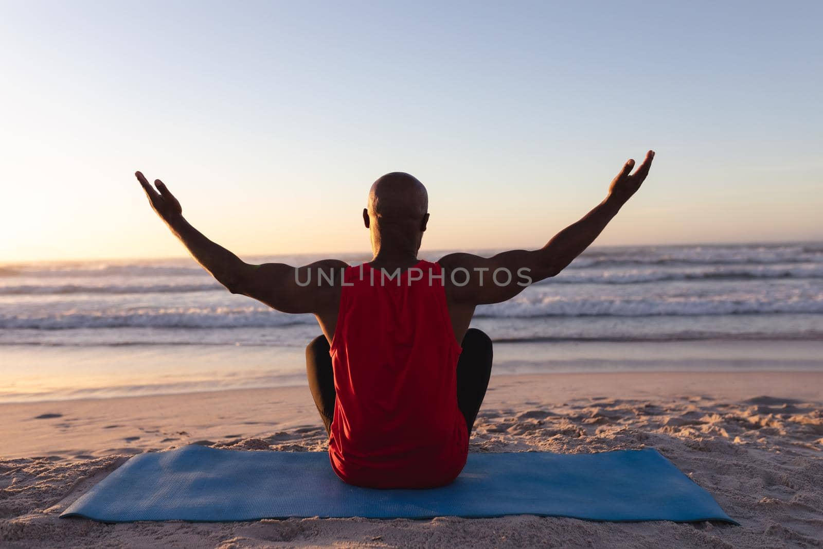 Rear view of senior african american man with arms wide open practicing yoga at the beach by Wavebreakmedia