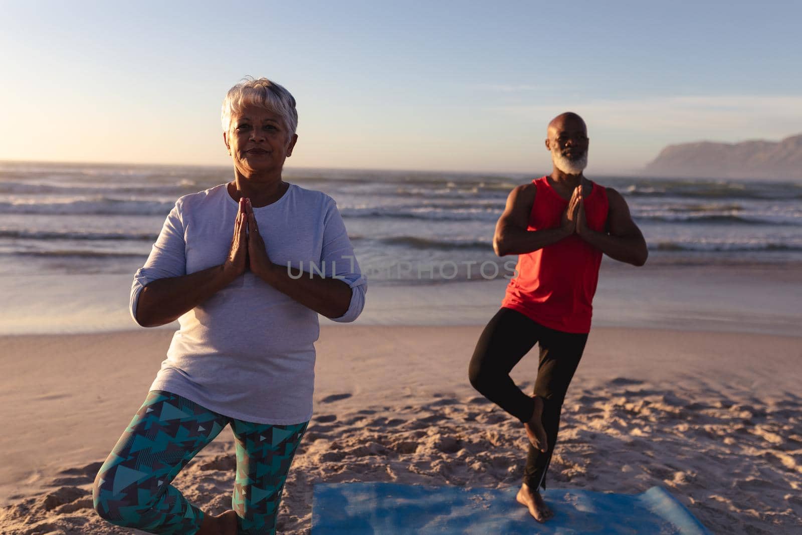 Senior african american couple with folded hands meditating and practicing yoga together at the beac by Wavebreakmedia