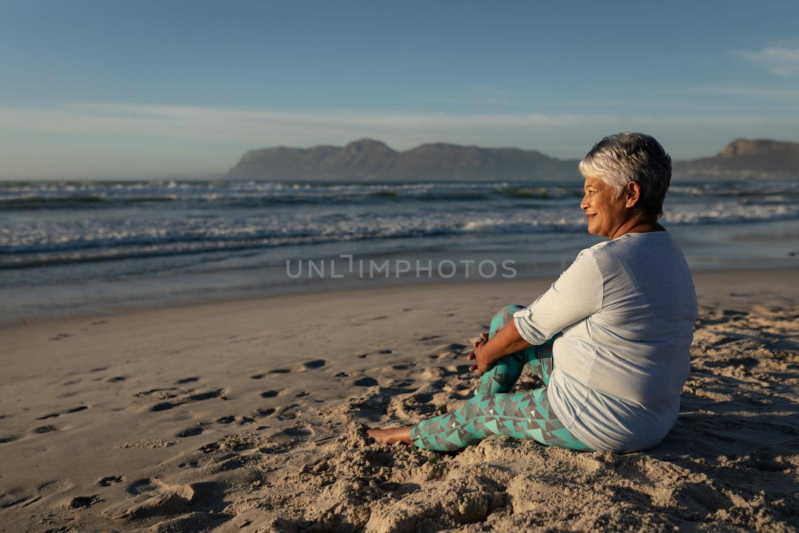 Senior african american woman smiling while sitting on the beach by Wavebreakmedia