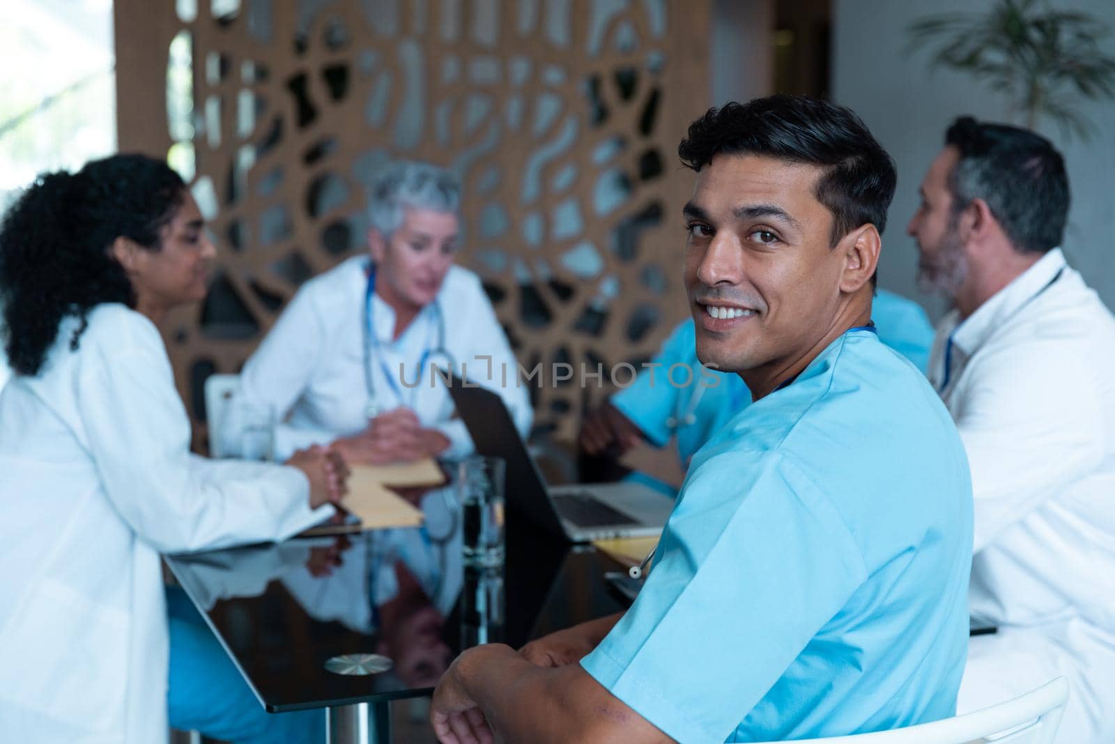 Diverse male and female doctors wearing face masks sitting in hospital having discussion by Wavebreakmedia