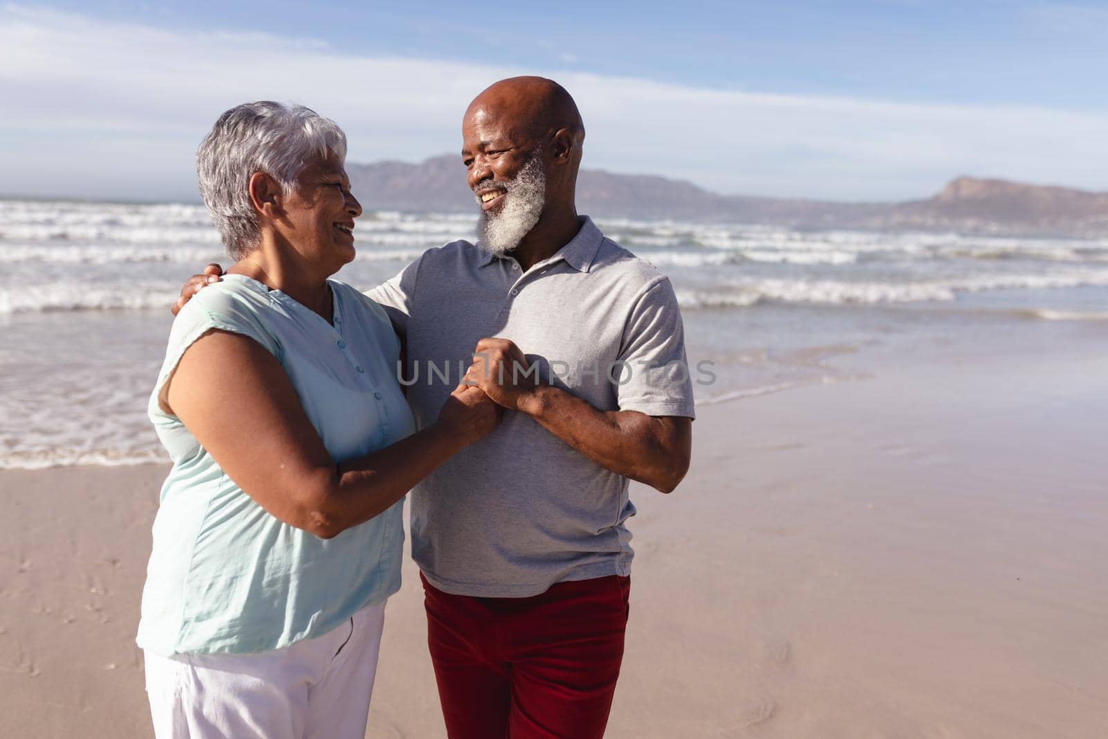 Happy senior african american couple embracing each other on the beach by Wavebreakmedia