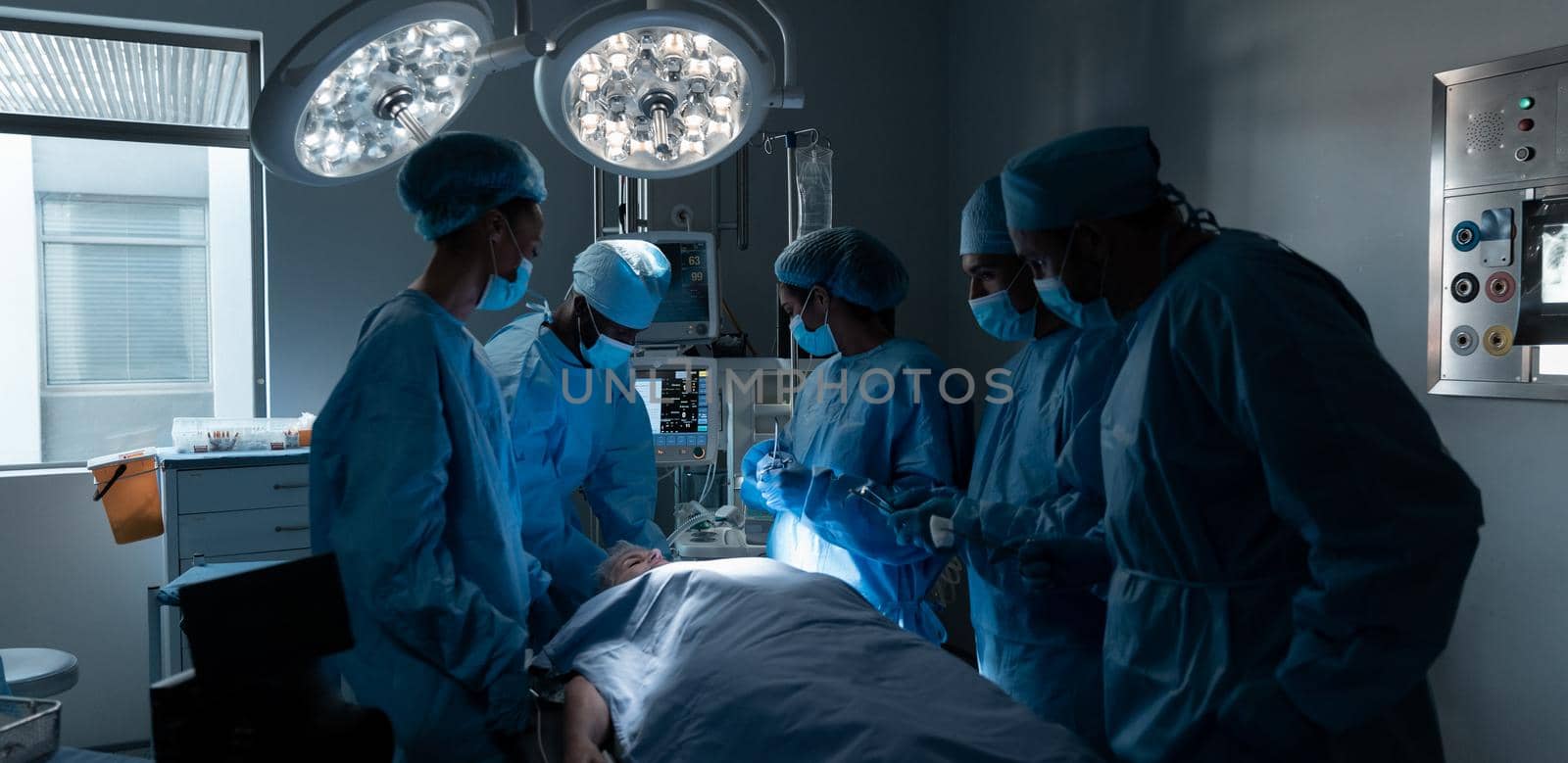 Diverse surgeons with face masks and protective clothing during operation in hospital by Wavebreakmedia