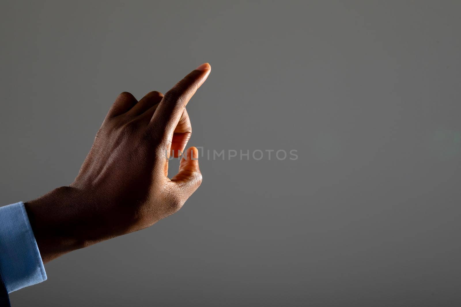 Close up of businessman touching invisible screen against grey background by Wavebreakmedia