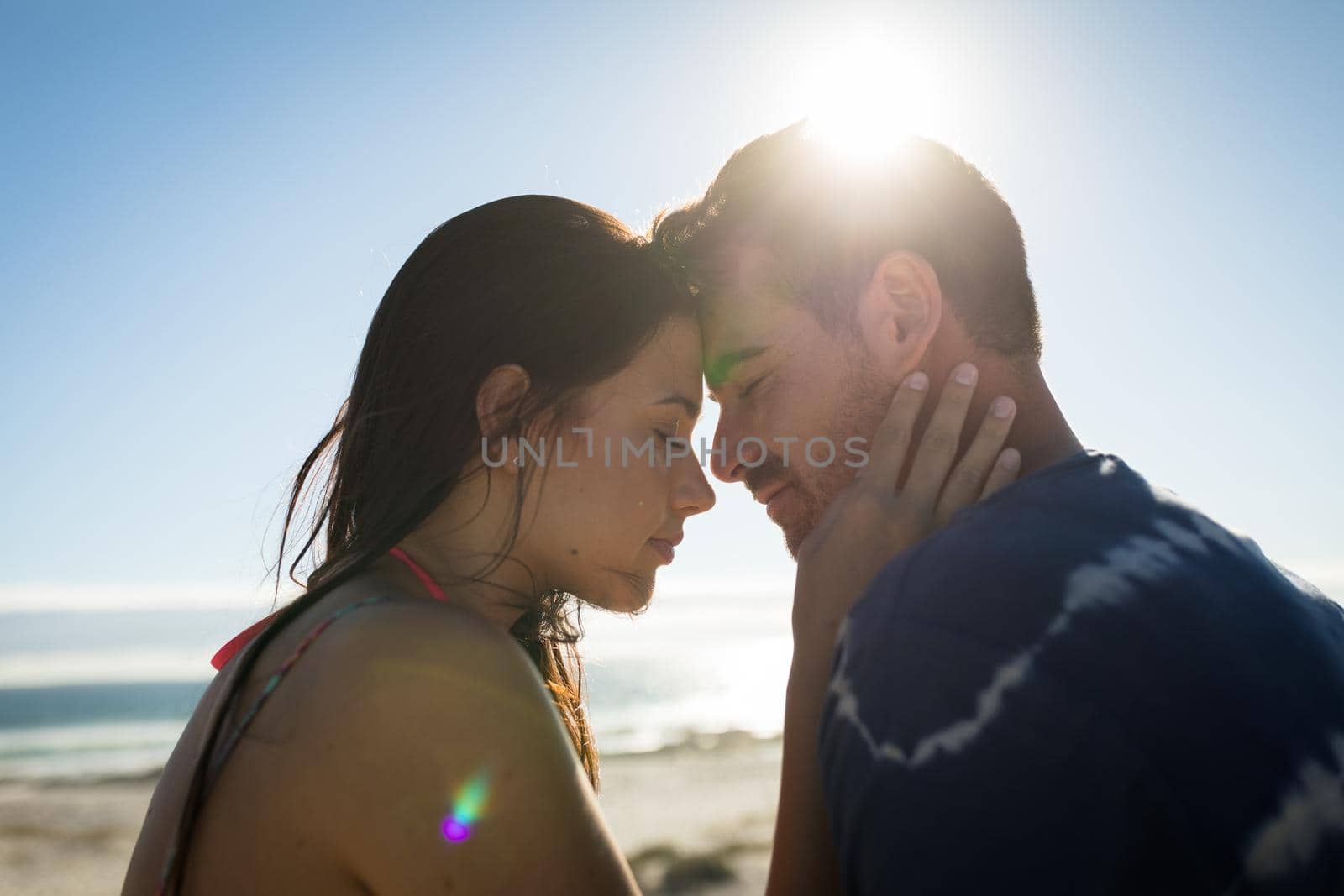 Happy caucasian couple on beach at the sea touching foreheads. love, romance and beach break summer holiday.