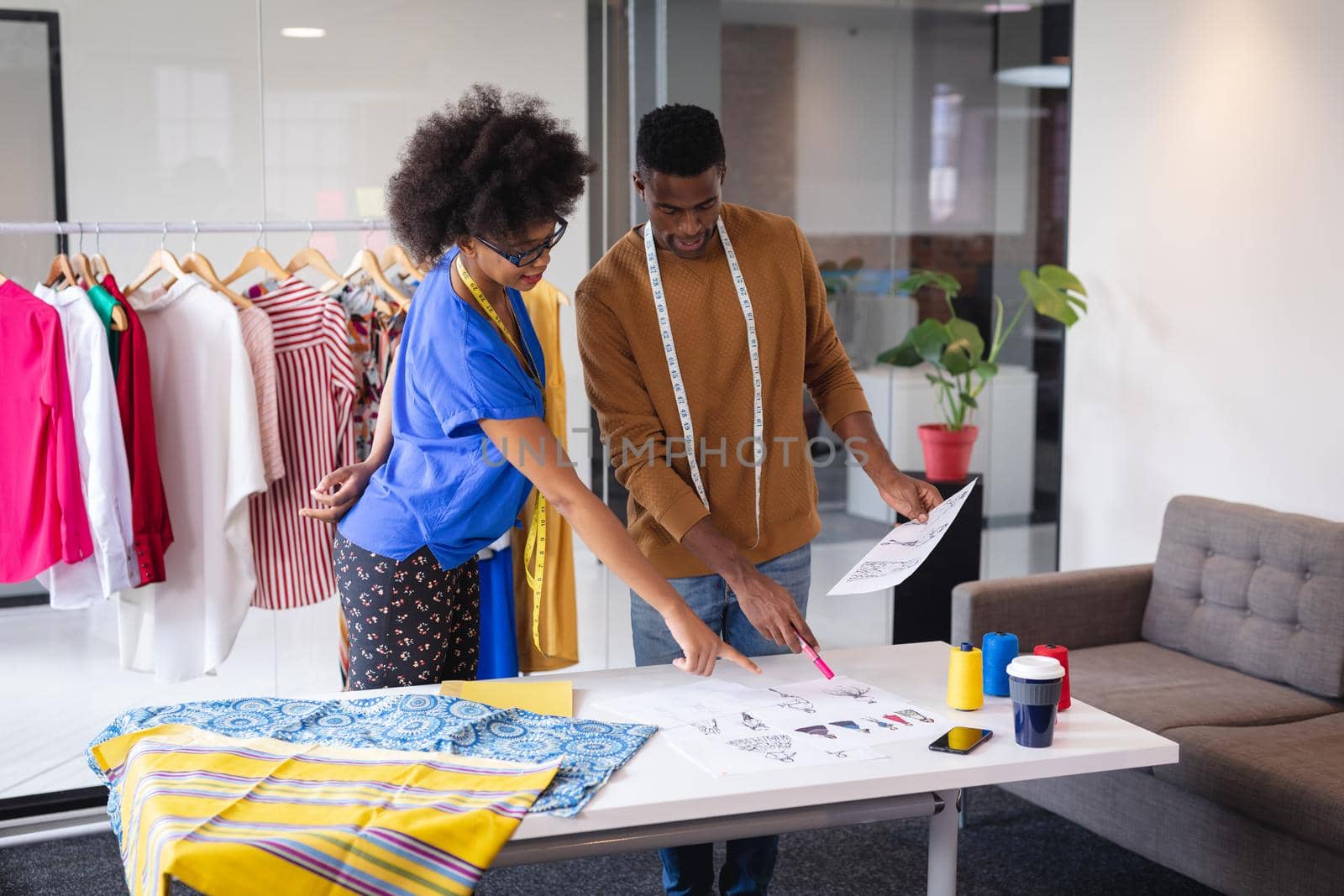 Diverse male and female fashion designers at work discussing and looking at sketches by Wavebreakmedia