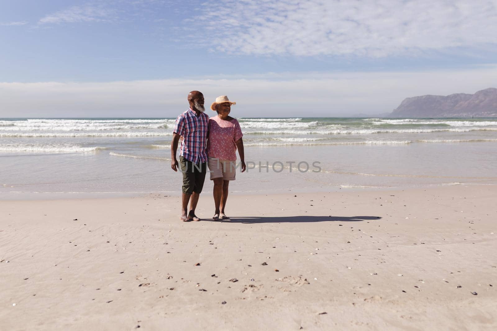 Happy senior african american couple walking together on the beach by Wavebreakmedia