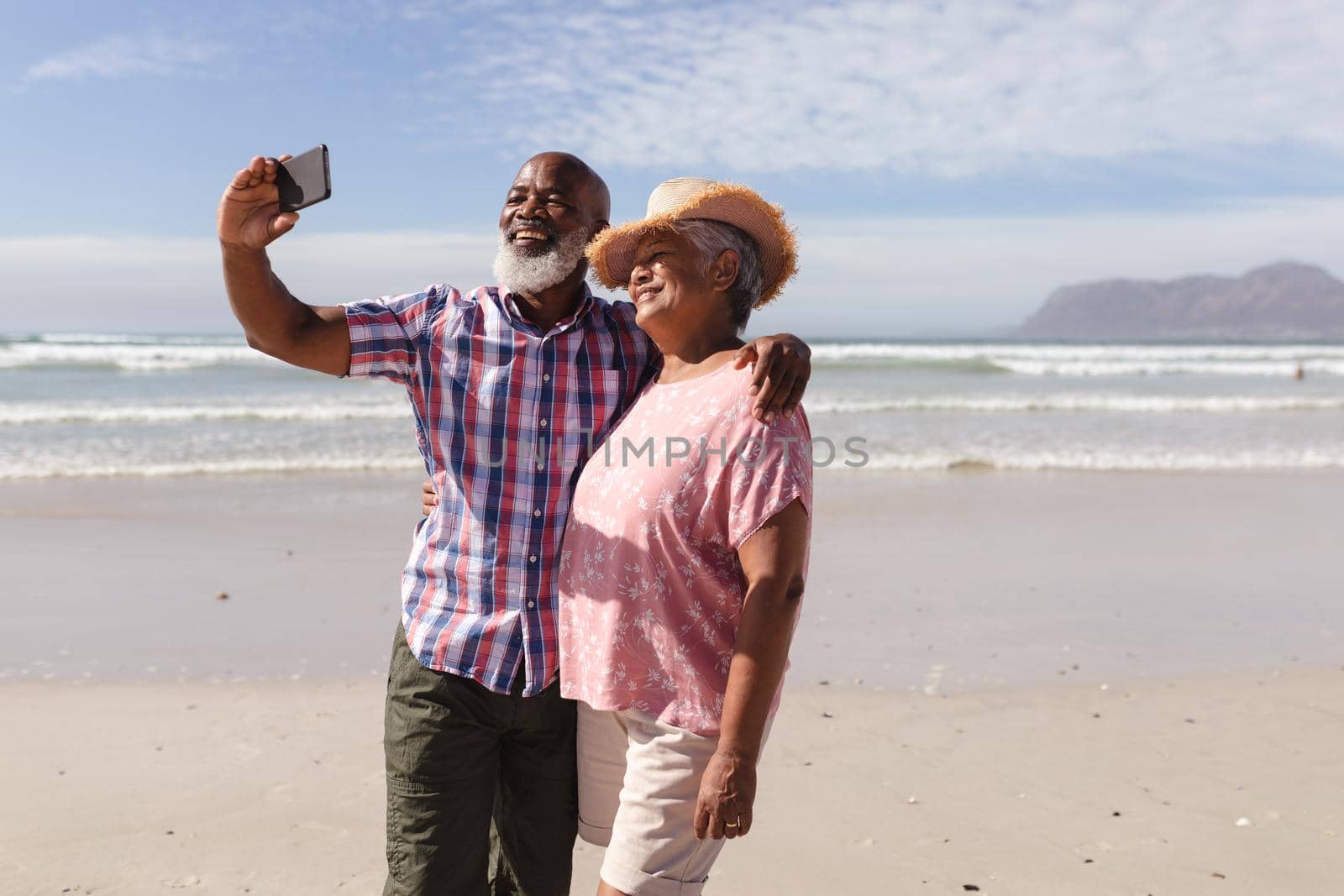 Happy senior african american couple taking a selfie from smartphone on the beach. travel vacation retirement lifestyle concept