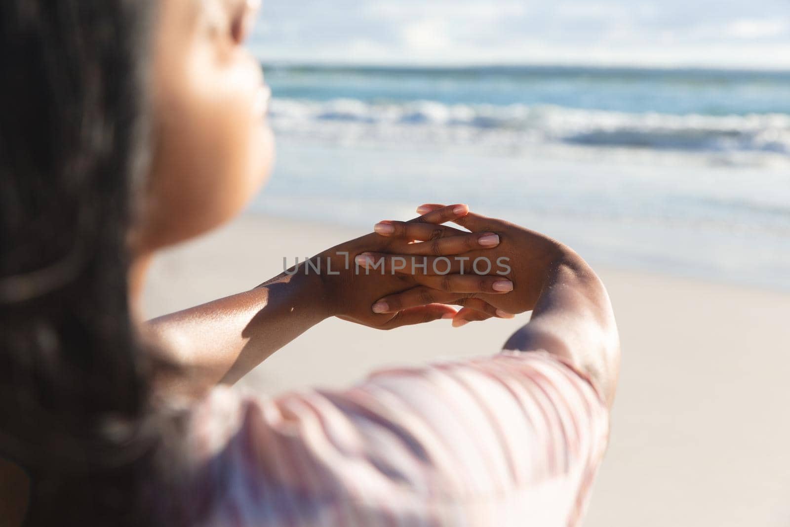 Mixed race woman on beach holiday stretching hands. outdoor leisure vacation time by the sea.