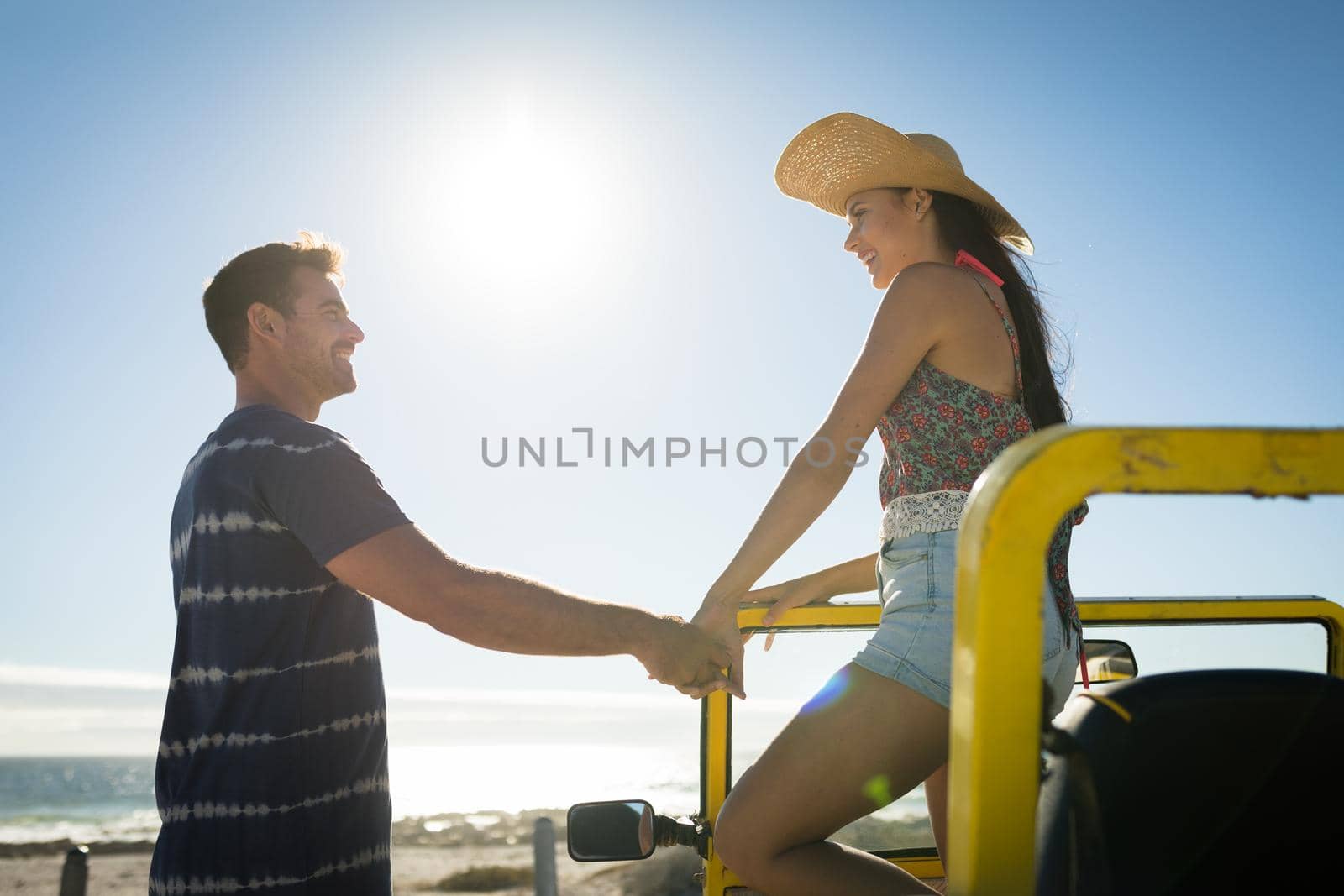 Happy caucasian couple on beach by the sea holding hands. beach vacation break on summer holiday road trip.