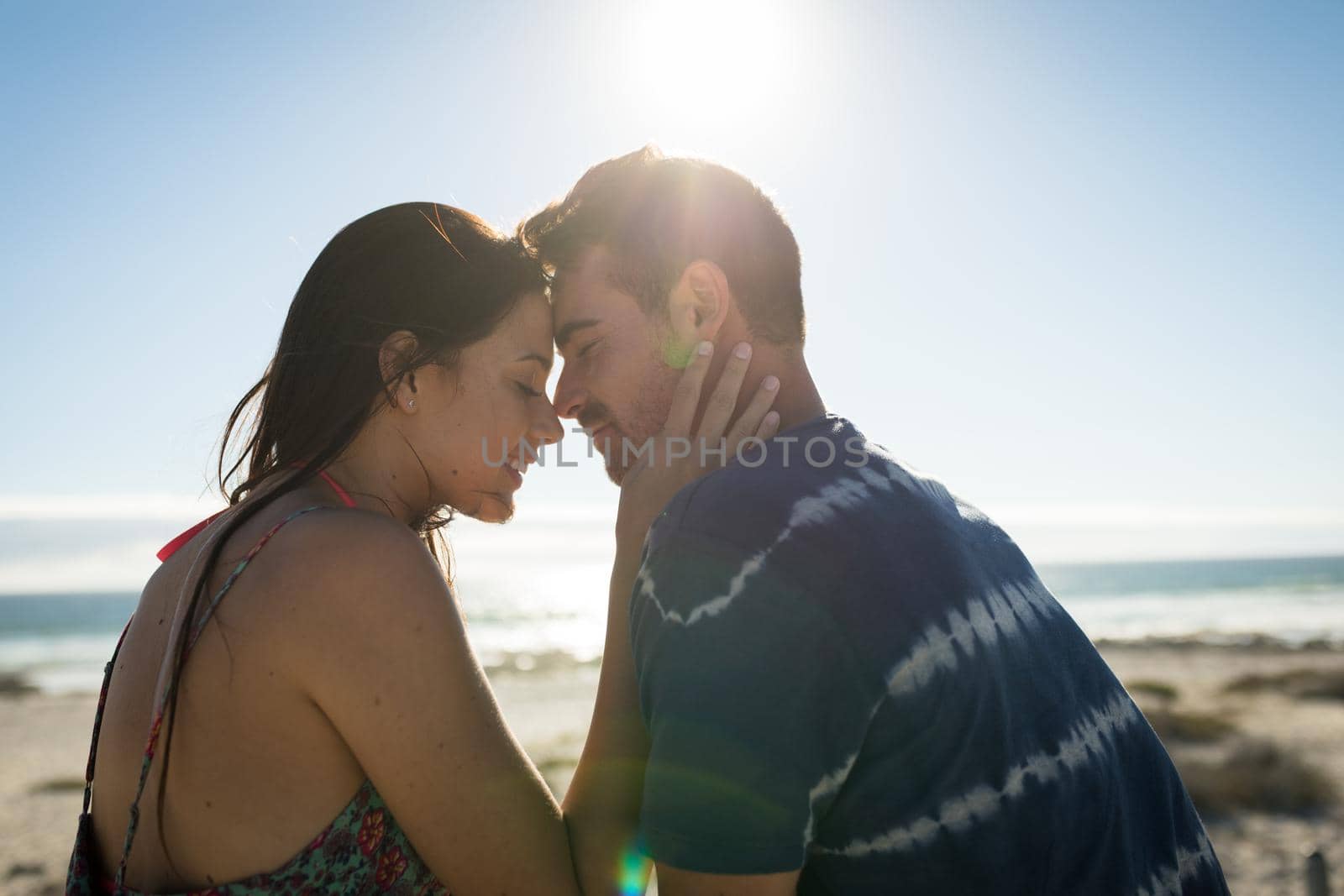 Happy caucasian couple on the beach touching foreheads. love, romance and beach break summer holiday.