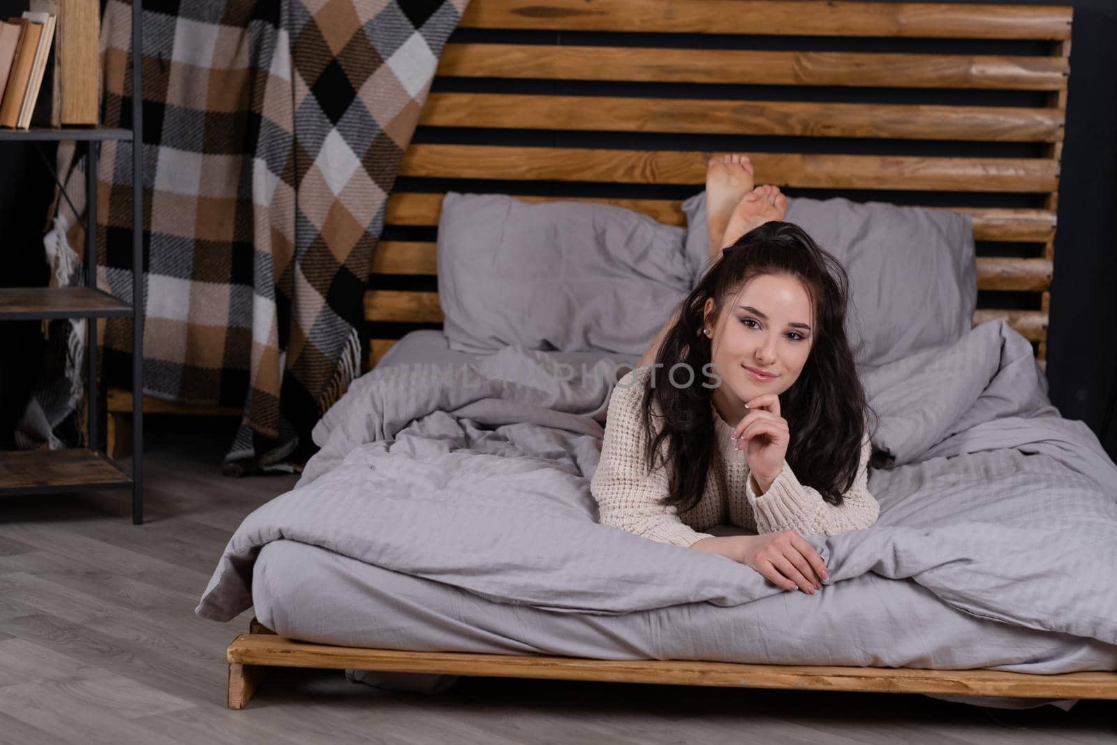 pretty woman indoor portrait. Young beautiful woman in warm knitted sweater at home on bed in morning. fashion. happy, sexy legs, lazy, sleepy.