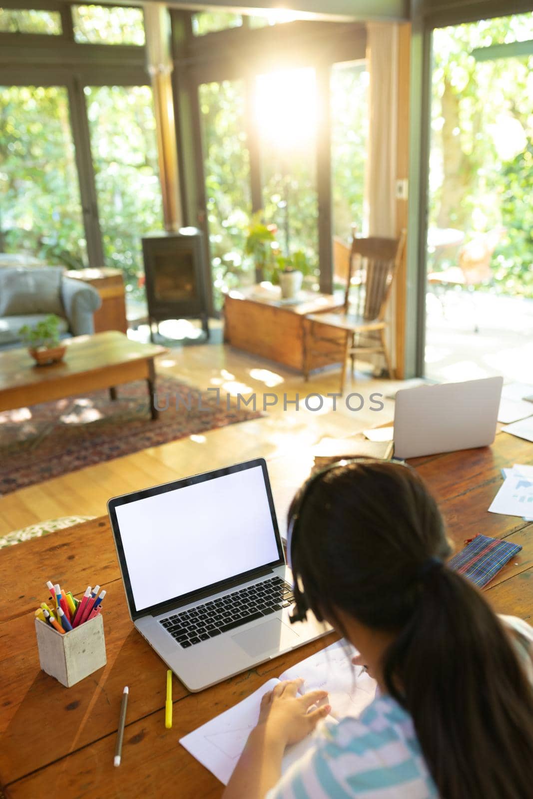 Asian girl using laptop with blank screen, writing, learning online. at home in isolation during quarantine lockdown.