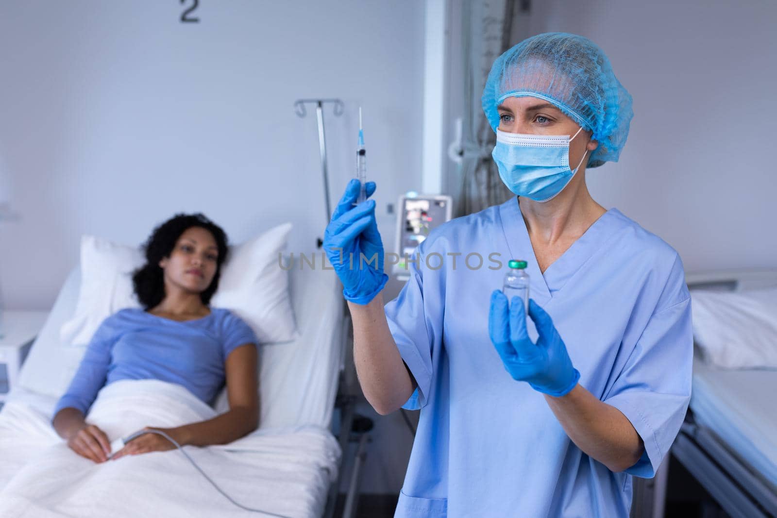 Caucasian female doctor wearing face mask preparing vaccination for african american female patient. medical professional at work during coronavirus covid 19 pandemic.